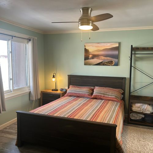 Bedroom:  cute bedroom with queen-size bed, ceiling fan, private streaming television, dresser, closet, nightstand, and lamp.
