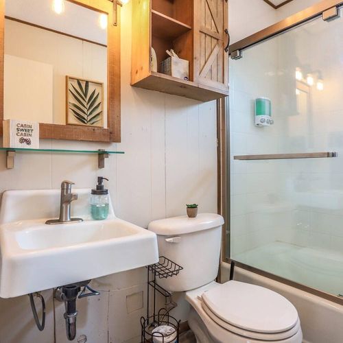 - enjoy warm, cozy vibes with wood cabinetry, rope towel hook, and nature artwork
- glass shower doors and modern fixtures meet rustic charm in perfect harmony
- thoughtful details like soap dispensers and a mini succulent add a personal touch