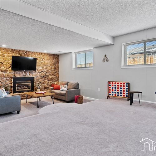 - spacious lower level with sectional seating, mounted tv, and stone fireplace wall
- game ready with connect four and table space for indoor family fun and relaxation
- bright natural light from two windows keeps the basement feeling open and fresh
