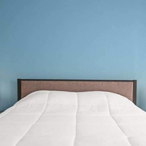 Duerma con estilo en nuestro sereno dormitorio, adornado con impecables sábanas blancas y frente a relajantes paredes azules.