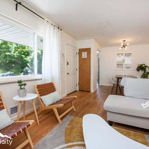 - light filled open layout connects the cozy lounge to the dining space
- natural wood tones and earthy textures create a welcoming, modern vibe
- large front window brings in serene greenery and soft natural light