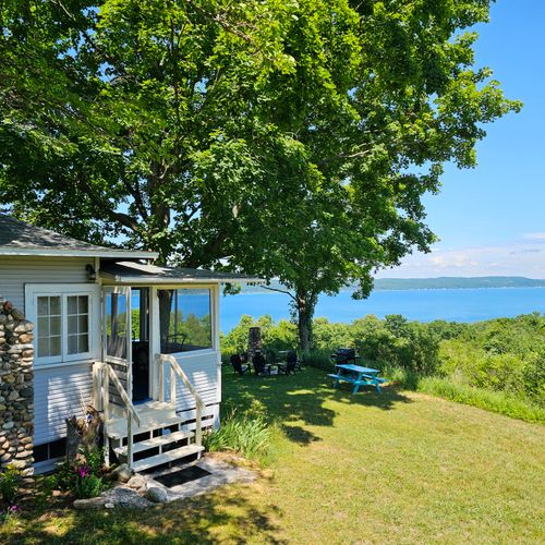 EXTERIOR:  The front entrance with the picnic table, grill, bonfire ring, and Crystal Lake in the background