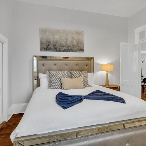 Comfort meets style in this beautifully detailed bed, featuring a unique headboard and soft, inviting pillows. Perfect for unwinding in a cozy, restful setting after a day in New Orleans.