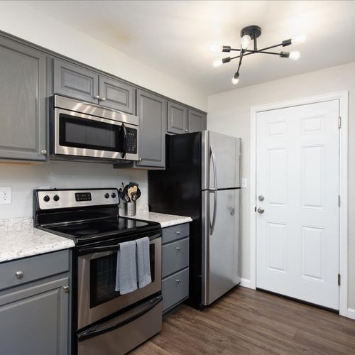 The kitchen features beautiful countertops and modern appliances, including refrigerator, stove, oven, microwave and coffee maker.