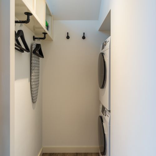 A bright and organized laundry space equipped with a full washer/dryer, hangers, and storage essentials.