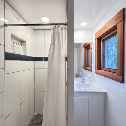 Upstairs shared bathroom with a single vanity and  custom-tiled shower