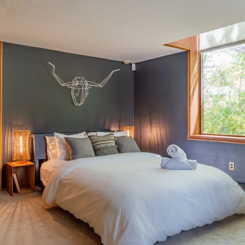 An immense picture window fills this moody and chic bedroom with light.
