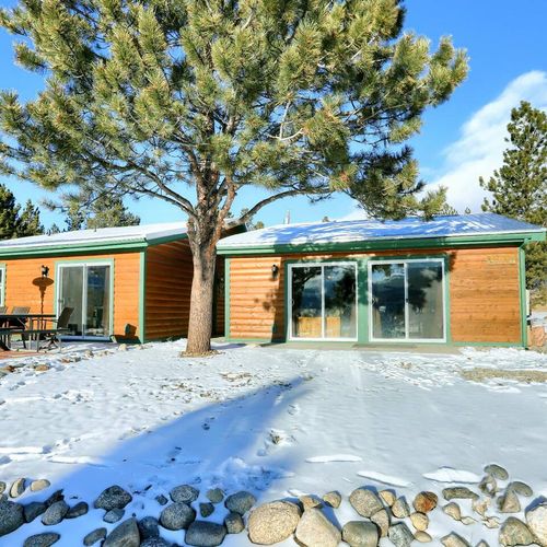 Cozy cabin duplex surrounded by pine trees and snow, perfect for serene mountain getaways.
