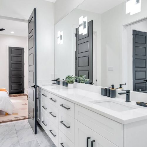 Elegant double-sink bathroom w/ marble walls & warm-toned wood vanity.