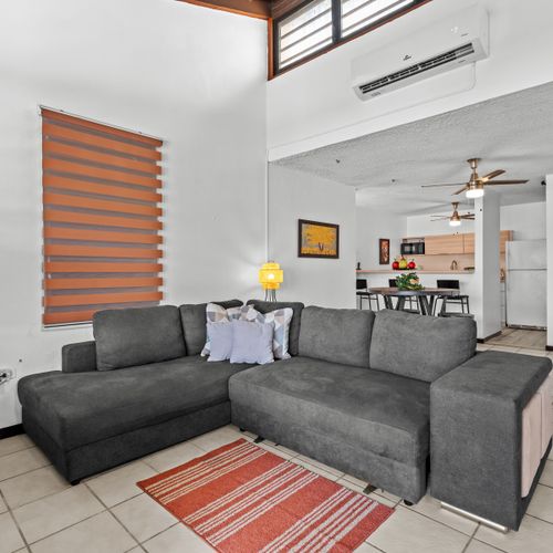 Unwind in our spacious living room featuring a plush gray sectional sofa, perfect for relaxing or enjoying a movie night.