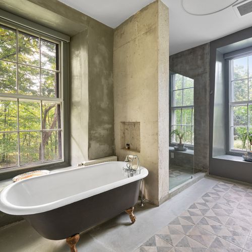 A clawfoot tub set amongst cement is one of many stylish juxtapositions throughout the house.