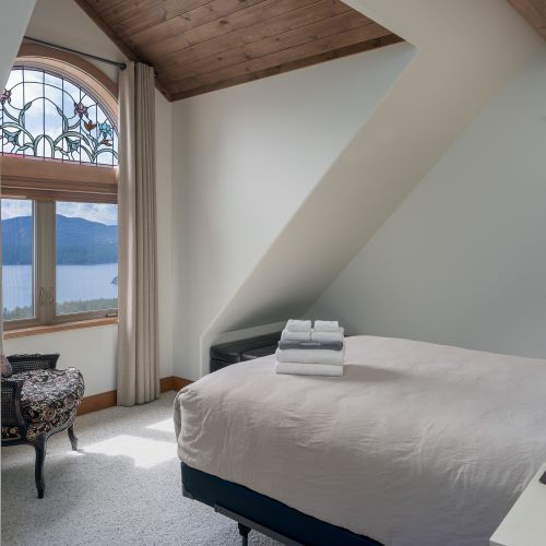 Guest bedroom with a queen bed,  reading area and water views.