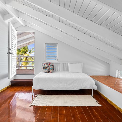 Sunlight & style. This dreamy corner bedroom invites in the breeze with tropical views and cozy vibes.