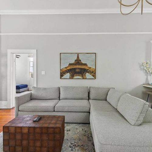 Spacious and stylish living area featuring a cozy sectional, exposed brick fireplace, and modern decor—a perfect spot to relax after exploring New Orleans.