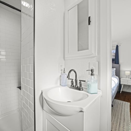 The remodeled en suite bathroom features a walk in shower, single vanity and eclectic floor tiles throughout.