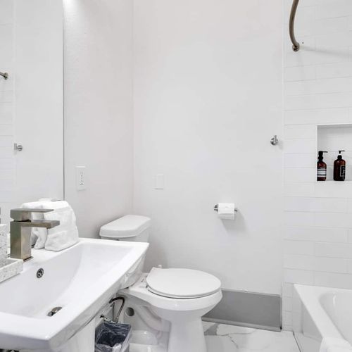 Clean, bright bathroom w/ white fixtures, sink & toilet — simple & refreshing.