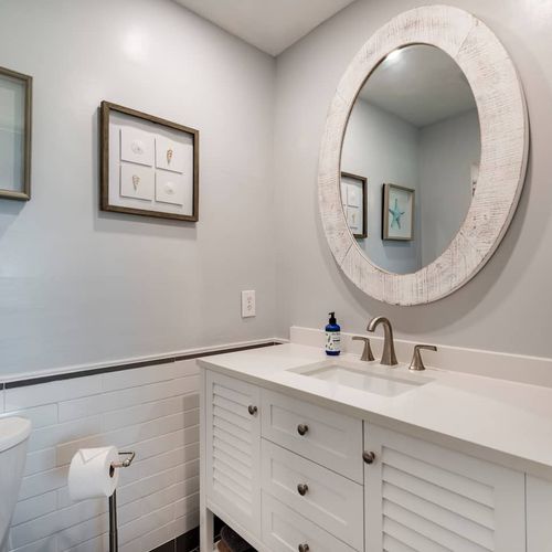 This redesigned bathroom features a new freestanding vanity with reclaimed wood mirror and a walk-in shower.