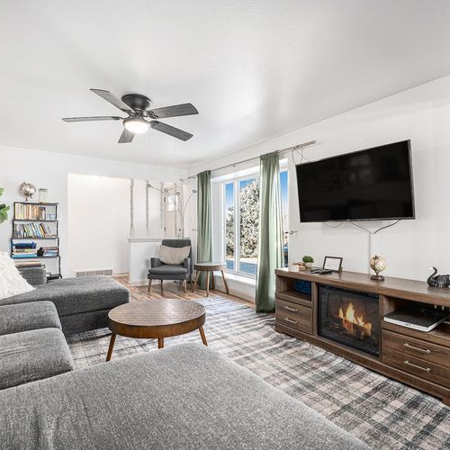 - relax in this stylish living room with a plush sectional sofa and cozy fireplace
- enjoy movie nights on the wall mounted smart tv in a bright, inviting space
- large windows with soft drapes bring in natural light and garden views