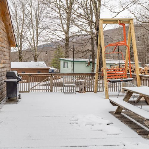 The back deck off the kitchen- complete with a grill, picnic table, string lighting, and swing made from a ski lift!