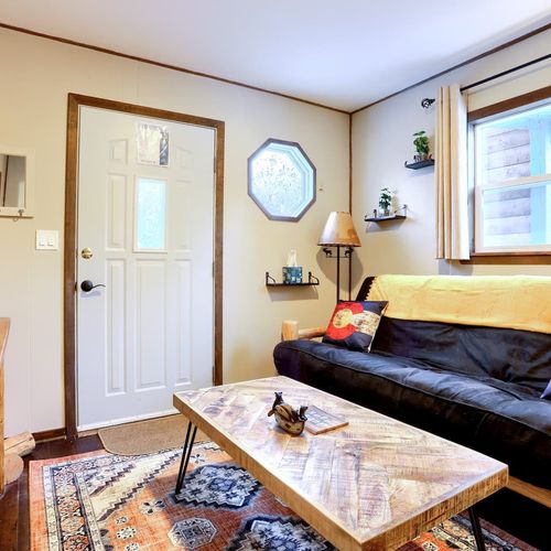 - step inside a welcoming space styled with cabin accents and colorado pride
- plush seating, boho rug, and curated shelves create a warm and artistic feel
- natural light fills the room through a front-facing window and door glass