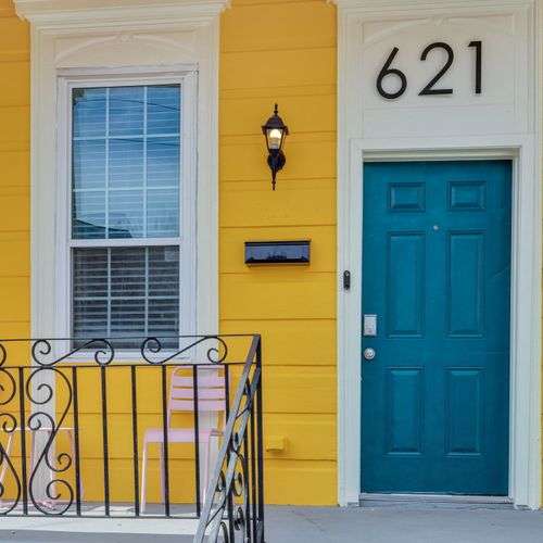 Vibrant yellow exterior w/ a teal door & classic ironwork — full of character.