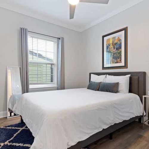 Third bedroom w/ queen bed & local NOLA art adding character to the space.