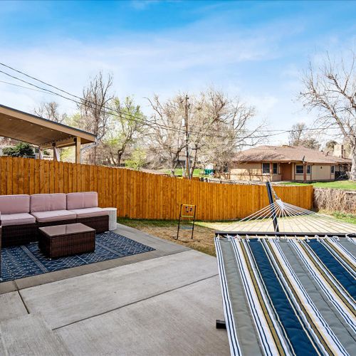 - step out onto the back patio featuring a cozy sectional, rug, and café lighting