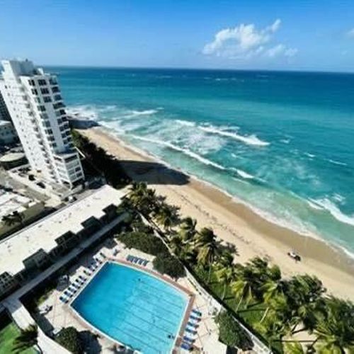 Stunning aerial view of beachfront living—where the turquoise waves meet a sparkling pool oasis.