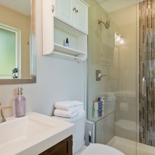 Relax and rejuvenate in the shared bathroom, featuring a walk-in glass door shower and all the basic amenities you need.