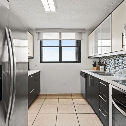 Indulge in culinary delights in our sleek kitchen, boasting stainless steel appliances and a chic mosaic backsplash.