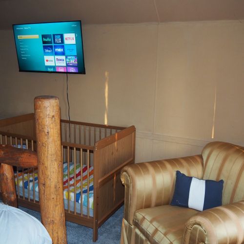 Bedroom #4 (second floor):  features a queen-size bed, private television, sofa bed, comfy chair, ceiling fan, baby crib, and a dresser.