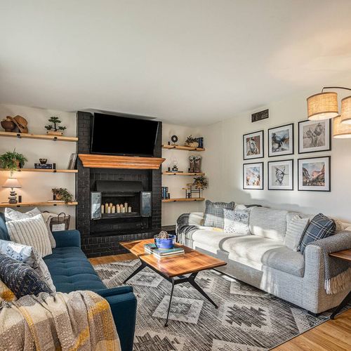 - twin couches face a central fireplace with wood mantle and surrounding built ins
- unique lighting and curated art wall add character to this inviting lounge
- stylish yet cozy for relaxing with movies, books, or board games