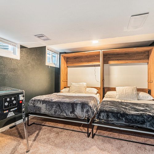 In this versatile game room, two murphy beds elegantly fold down to provide additional sleeping space, seamlessly blending comfort with functionality.