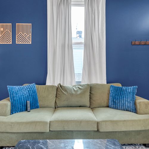 Bright living room w/ a bold navy accent wall & cozy seating for relaxing.