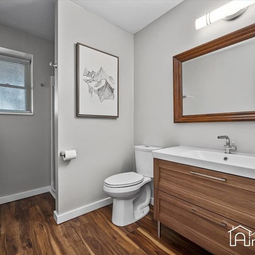 - updated bathroom with sleek wood vanity, large framed mirror, and walk in shower
- contemporary design pairs warm floors with cool gray walls for a fresh clean look
- practical layout with soft lighting ideal for any morning routine