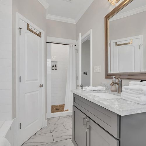 Fresh primary bathroom w/ marble countertop, sink & a clean, modern finish.