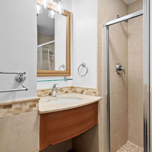 Modern and pristine bathroom featuring a vanity with a stylish mirror and a refreshing shower.