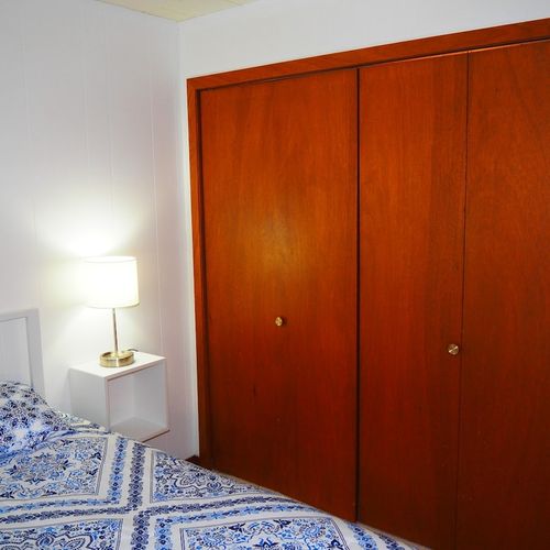 Bedroom #1:  features a queen-size bed, nightstands with lamps, ceiling fan, chair, dresser, closet, and full-length mirror.