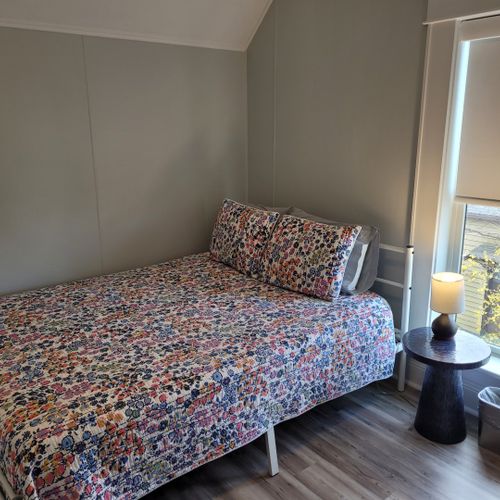 Bedroom #4 (second floor):  features a queen-size bed, twin bed, window a/c unit, ceiling fan, nightstand, lamp, dresser, and a closet.