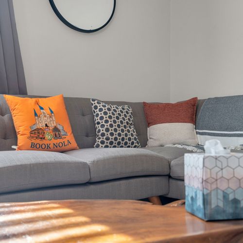 Cozy gray sofa w/ vibrant throw pillows & local Book NOLA touches.