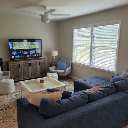 Living room:  the living room features a cozy sectional that unfolds into a double bed. There is also a coffee table, hutch, ceiling fan, a couple portable chairs, a dog bed, and a large smart tv.