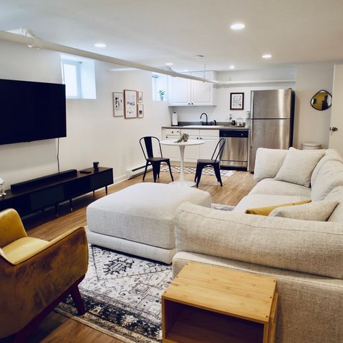 Basement living room upgraded with seating for all and a tv.