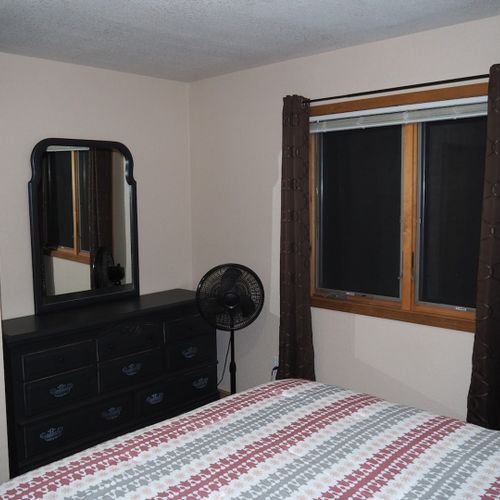 Bedroom #1 (main floor):  features a queen-size bed, nightstands, dresser, mirror, pedestal fan, and closet.