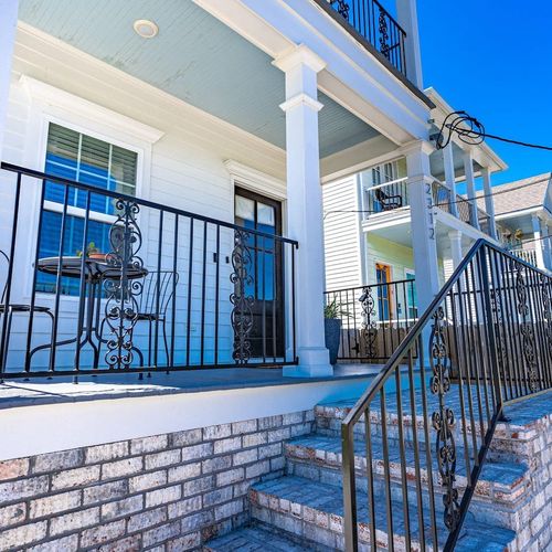 Charming front patio w/ classic ironwork — a welcoming entry to come home to.