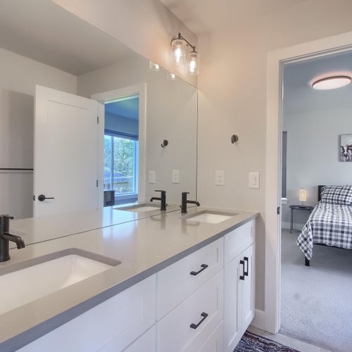 - dual vanity setup with matte black fixtures and white cabinetry connects to bedroom