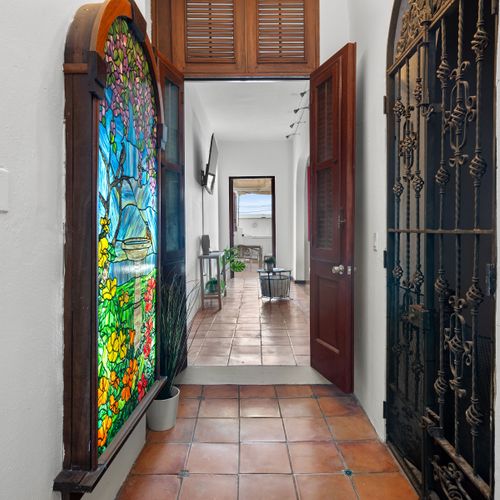 Stroll down the hallway, highlighted by a vibrant stained glass window and an elegant, intricate iron gate.