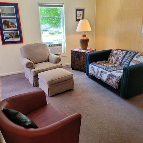 Living room:  features a loveseat, comfy chairs, live-streaming television with roku, and a ceiling fan.