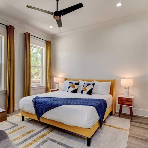 Bright first-floor master bedroom w/ a cozy bed & warm natural light.