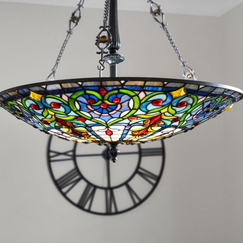 Stained-glass chandelier casting warm, colorful light — a stunning centerpiece.