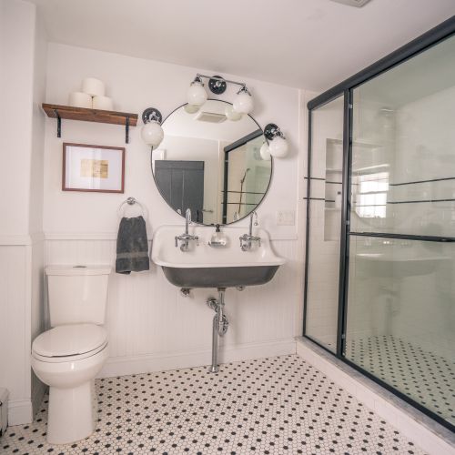 The primary bedroom's ensuite bath is updated with new accents like the rain shower, while tastefully honoring  early American design.